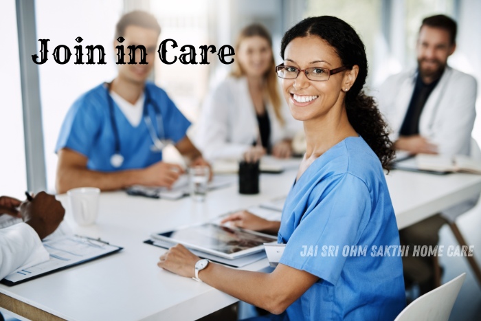 A smiling healthcare professional in a blue uniform at a meeting, surrounded by a diverse team of medical staff. This image represents the collaborative and supportive environment at Jai Sri Ohm Sakthi Home Care in Coimbatore. It emphasizes the invitation to join in care and contribute to high-quality home nursing and patient support services