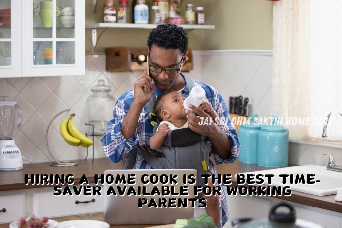 A father multitasking in the kitchen, holding a baby in a carrier while feeding the child with a bottle and talking on the phone. This image highlights the benefits of hiring a home cook as a time-saver for working parents, showcasing the services offered by Jai Sri Ohm Sakthi Home Care in Coimbatore